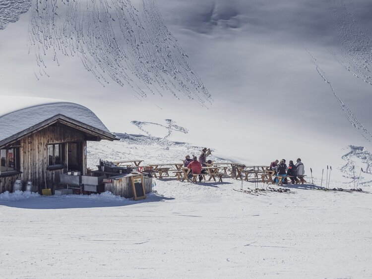 Tische und Bänke stehen vor der Nülli Bar bereit zum verweilen. | © Davos Klosters Mountains