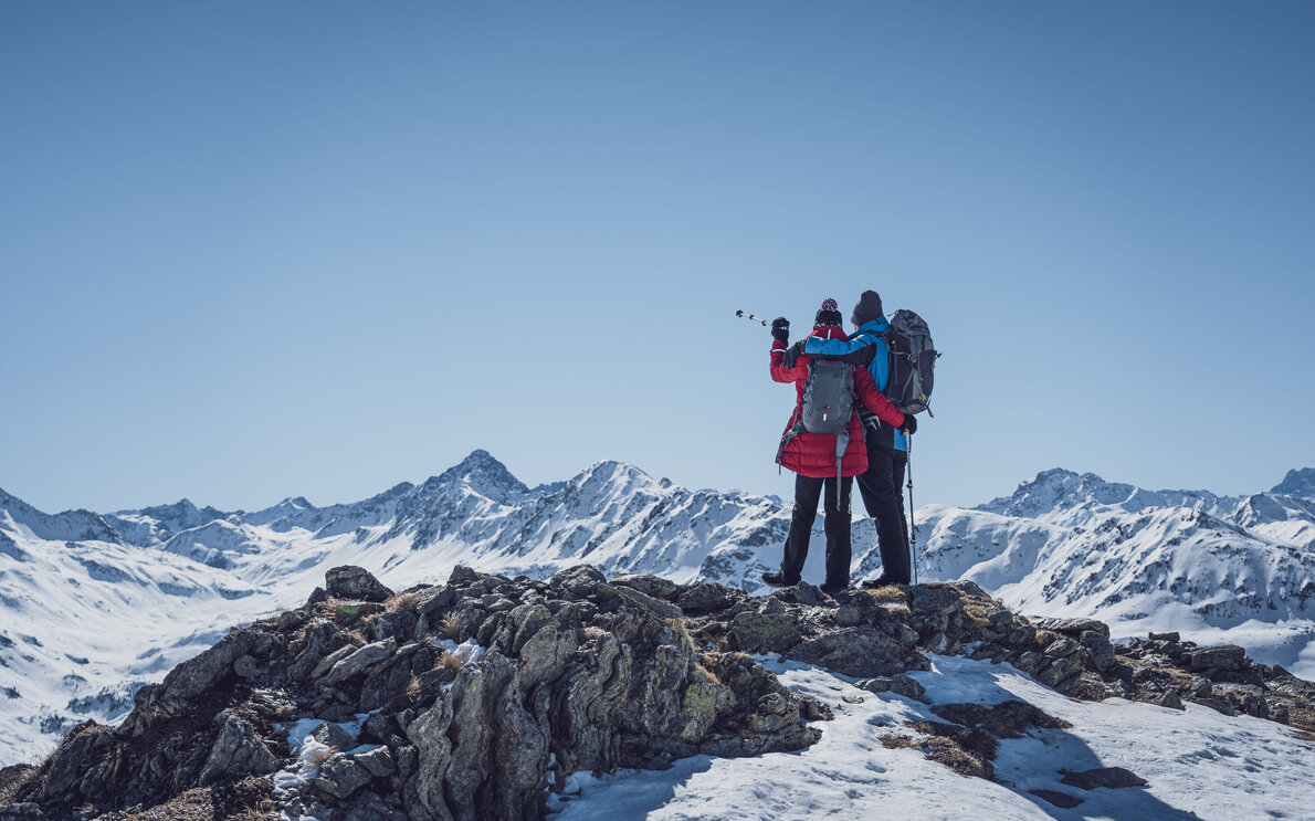 Zwei Winterwanderer auf Pischa stehen Arm in Arm und blicken auf das Schwarzhorn.  | © Davos Klosters Mountains