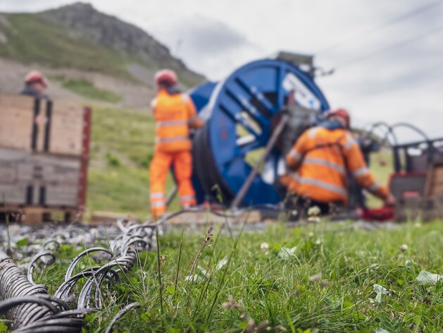 Das Stahlseil liegt am Boden, im Hintergrund wickeln es Arbeiter auf eine Spule. | © Davos Klosters Mountains