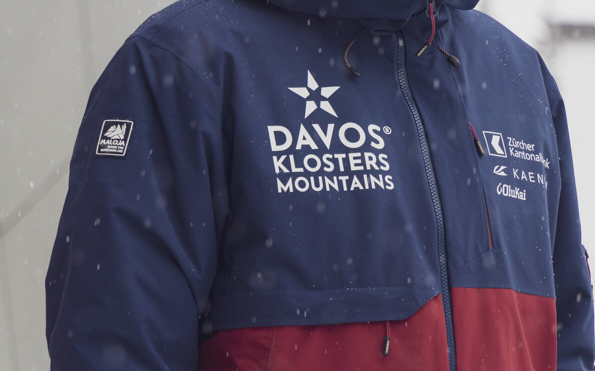 Die rot/blaue Jacke der Marke Maloja  gehört zur neuen Mitarbeiterkleidung der Davos Klosters Mountains.  | © Davos Klosters Mountains