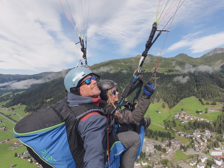 Der Pilot lässt den Gast den Gleitschirm lenken und sie fliegen über Davos. | © Davos Klosters Mountains