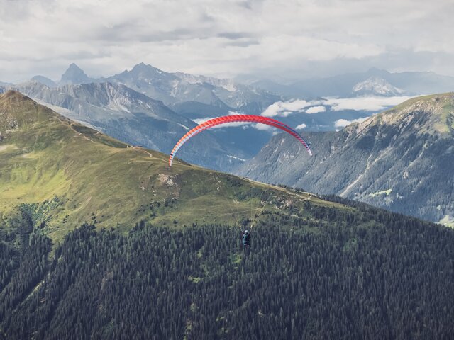 Der rote Gleitschirm fliegt zum Horizont in Richtung Rinerhorn.  | © Davos Klosters Mountains
