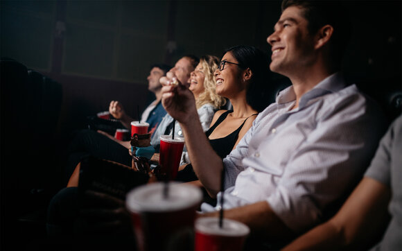 Eine Freundesgruppe schaut einen Film hat grossen Spass beim gemeinsamen Kinobesuch. | © Shutterstock