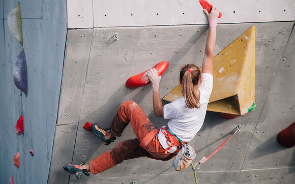Eine Frau klettert an einer überhängenden Wand in der Kletterhalle.   | © Shutterstock
