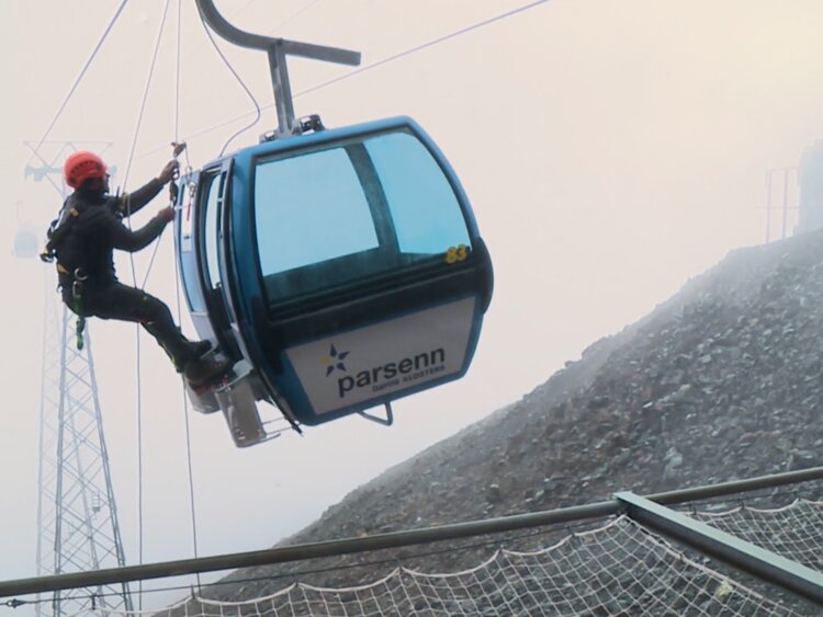 Eine Person hängt bei der Gondel und hat sie geöffnet. | © Rondo News Fokus - suedostschweiz.ch