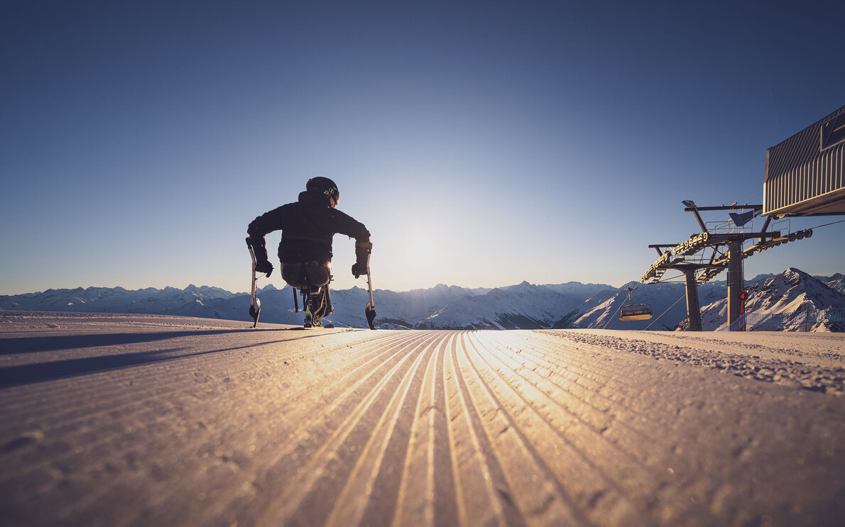 Monoskifahrer steht bei den ersten Sonnenstrahlen auf den perfekt präparierten Skipisten auf Parsenn.  | © Davos Klosters Mountains