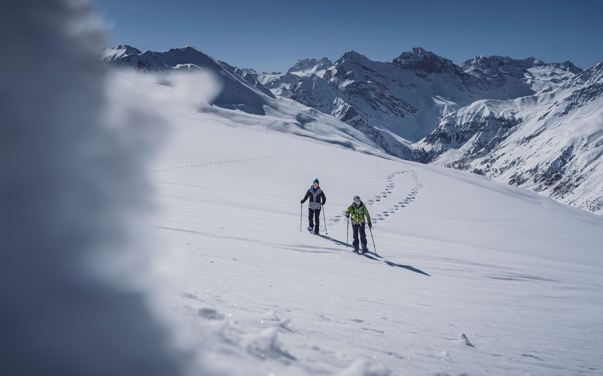 Zwei Personen beim Schneeschuhlaufen auf dem Jakobshorn mit Blick ins Sertig. | © Davos Klosters Mountains