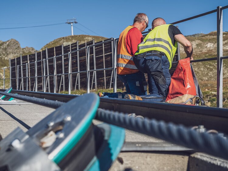 Zwei Mitarbeiter reparieren das Geländer auf der Parsennbahn im Sommer. | © Davos Klosters Mountains
