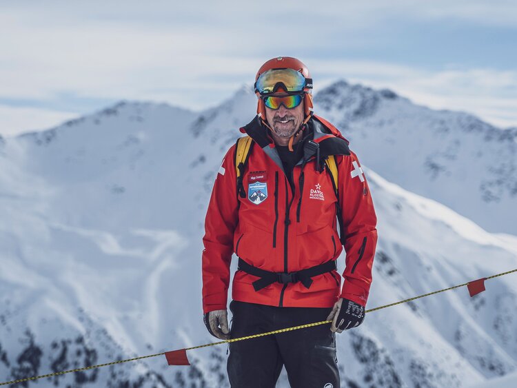 Mit roter Skijacke und Skier ausgestattet ist der Pisten- und Rettungschef im Skigebiet Rinerhorn unterwegs. | © Davos Klosters Mountains