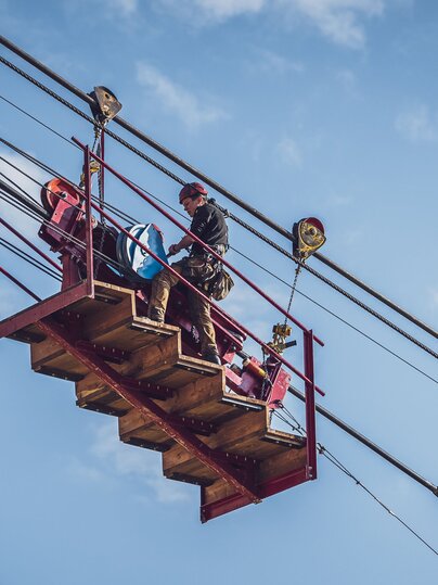 Der Arbeiter steht auf der sogenannten Meklmaschine mit welcher das Seil schrittweise auf den Berg gezogen wird. | © Davos Klosters Mountains