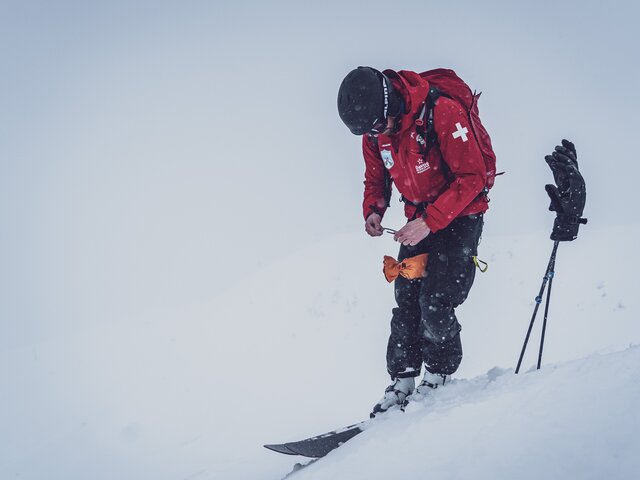 Der Patrouilleur steht im Schnee und zündet die Zündschnur der Sprengkörper.  | © Davos Klosters Mountains