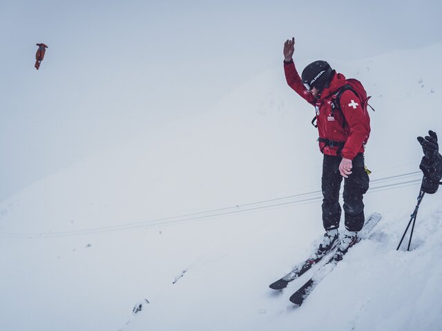 Der Mitarbeiter des Pisten- und Rettungsdienstes Jakobshorn wirft den gezündeten Sprengkörper in den Schnee.  | © Davos Klosters Mountains
