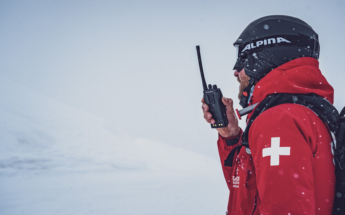 Der Patrouilleur ist auf dem Jakobshorn im Schnee unterwegs und spricht in sein Funkgerät.  | © Davos Klosters Mountains