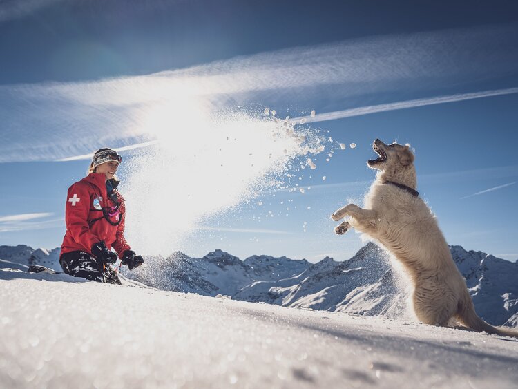 Patrouilleurin Seraina wirft ihrer Golden Retriever Hündin Emma Schnee in die Luft. | © Davos Klosters Mountains