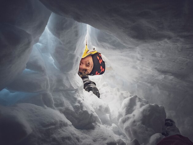 Der Lawinenhundeführer blickt bei einer Suchübung zur versteckten Person im Schneeloch. | © Davos Klosters Mountains
