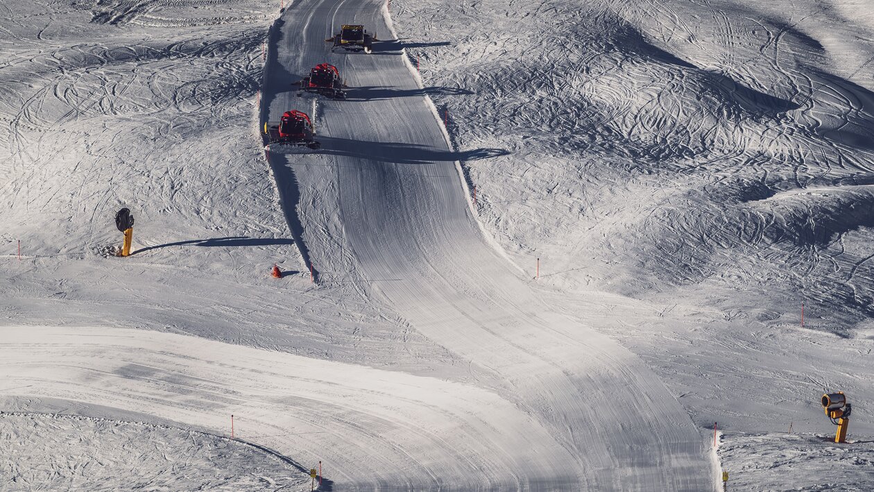 Vogelperspektive auf eine Piste auf dem Jakobshorn mit drei Pistenbullys, welche diese präparieren. | © Davos Klosters Mountains
