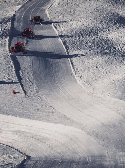 Vogelperspektive auf eine Piste auf dem Jakobshorn mit drei Pistenbullys, welche diese präparieren. | © Davos Klosters Mountains