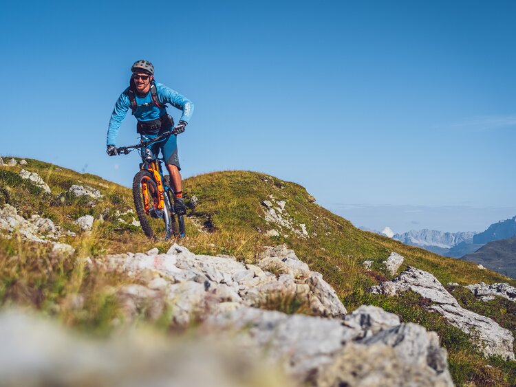 Biker in blauer Kleidung und mit orangem Mountainbike auf Gotschna Parsenn. | © Davos Klosters Mountains