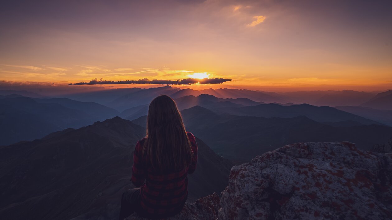 Wandrerin geniesst den Sonnenuntergang auf dem Gipfel. | © Davos Klosters Mountains 