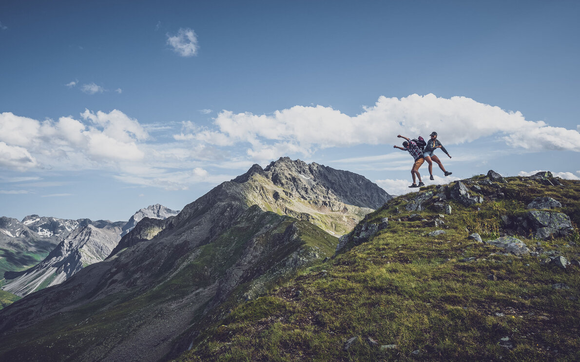 Zwei Wanderer auf Bergpfad springen in die Luft | © Davos Klosters Mountains 