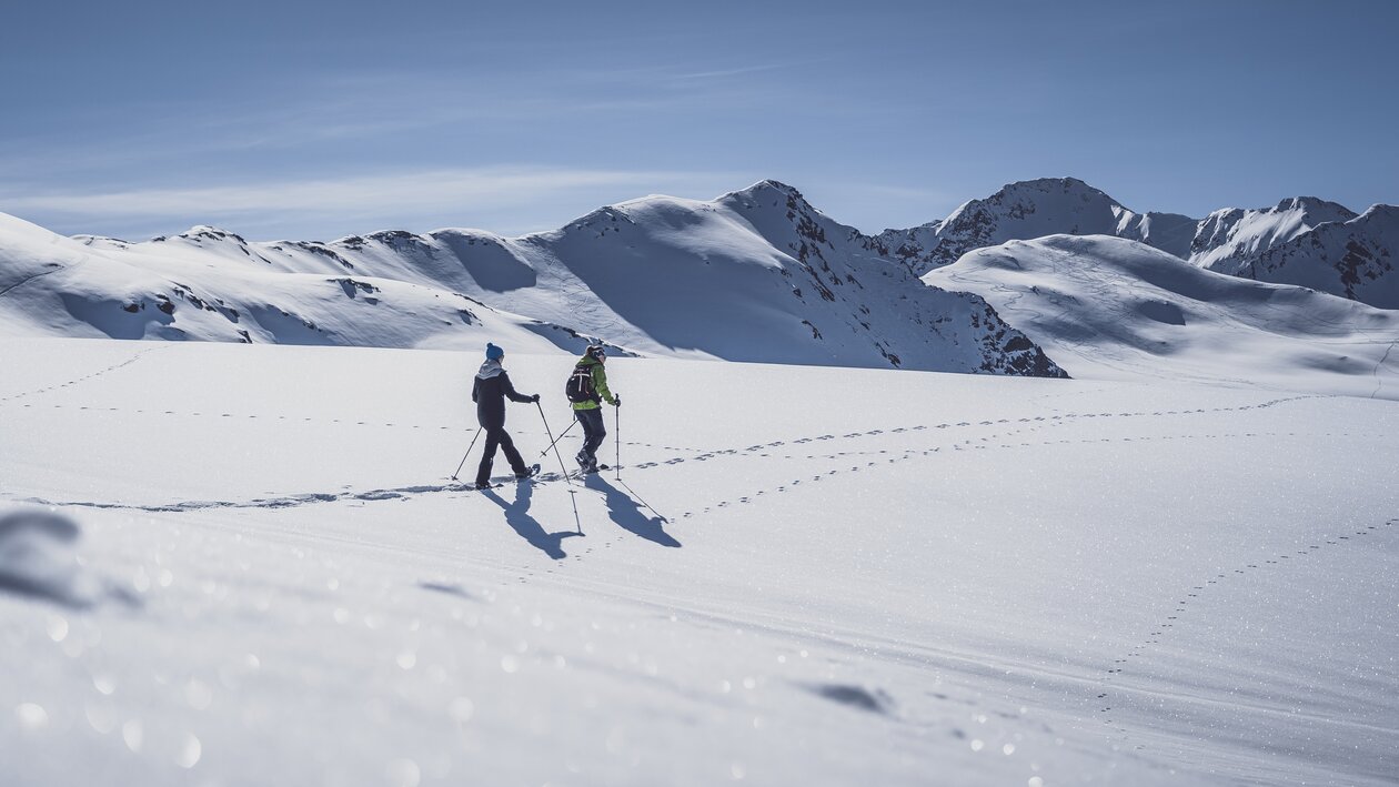 Two women walk through the deep snow on snowshoes. | © Davos Klosters Mountains