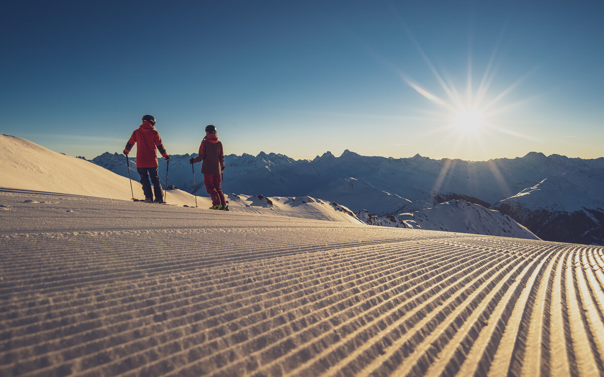 2 Skifahrer zum Sonnenaufgang auf der Piste | © Davos Klosters Mountains