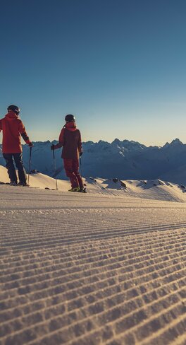 2 Skifahrer zum Sonnenaufgang auf der Piste | © Davos Klosters Mountains