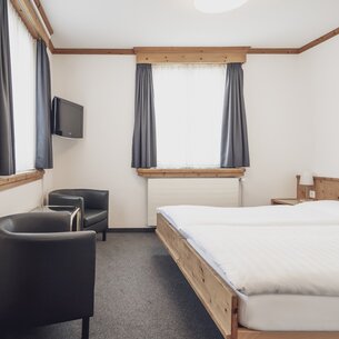 Hotelzimmer mit Doppelbett und Sesseln | © Davos Klosters Mountains