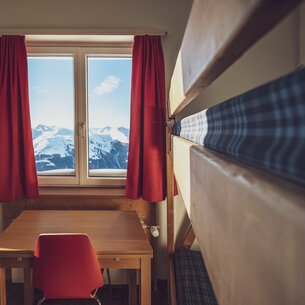 Double room with bunk bed, table, chair and window | © Davos Klosters Mountains 