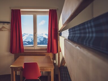 Zweibettzimmer mit Stockbett, Tisch, Stuhl und Fenster | © Davos Klosters Mountains 