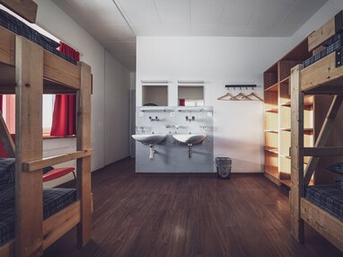 Mehrbettzimmer mit Stockbetten, Kleiderablagen und Lavabo | © Davos Klosters Mountains 