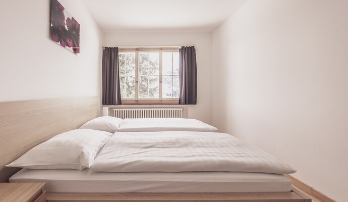 Double bed room with bed linen and a night table | © Davos Klosters Mountains 