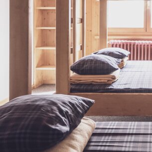 Mehrbettzimmer mit Doppelstockbetten und Kleiderablagen  | © Davos Klosters Mountains 