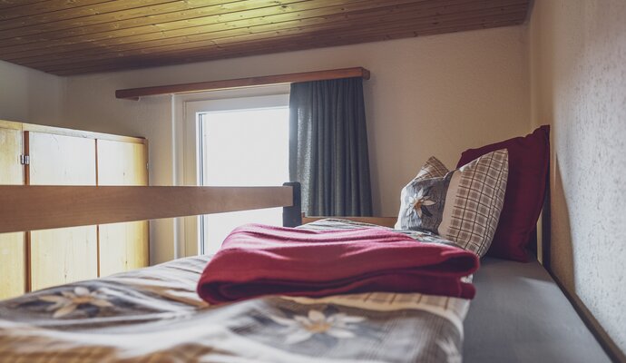 Bunk bed with blanket and a window | © Davos Klosters Mountains