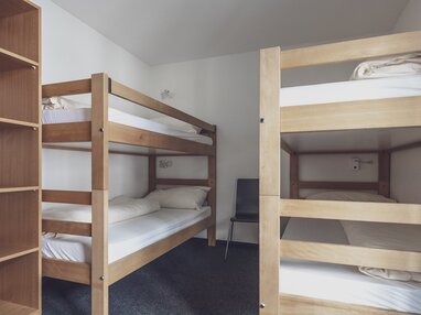 Einfaches Zimmer mit 2 Stockbetten und Kleiderablage  | © Davos Klosters Mountains 