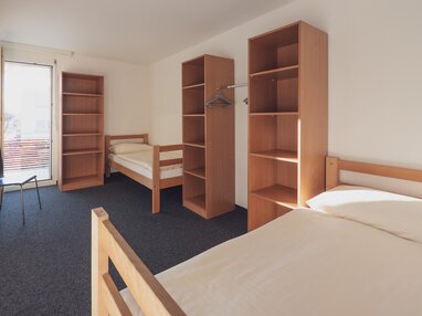 Einfaches Mehrbettzimmer mit Bettwäsche und Kleiderablagen | © Davos Klosters Mountains 