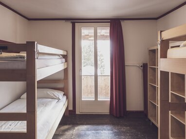Mehrbettzimmer mit Stockbetten und Kleiderablagen | © Davos Klosters Mountains 