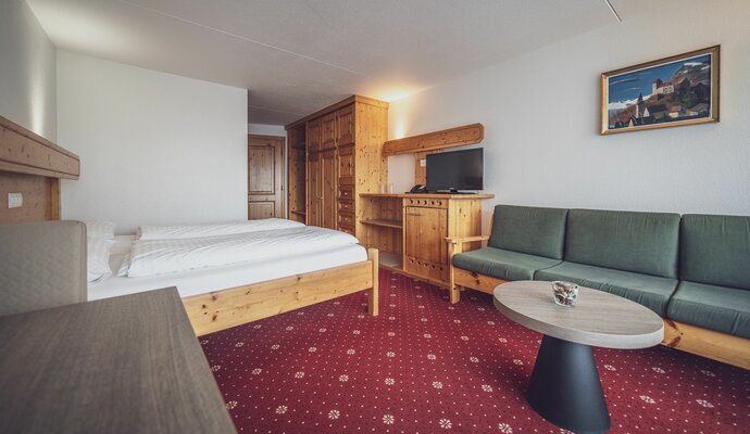 Doppelbettzimmer mit Teppichboden, Sitzsofa und Beistelltisch | © Davos Klosters Mountains