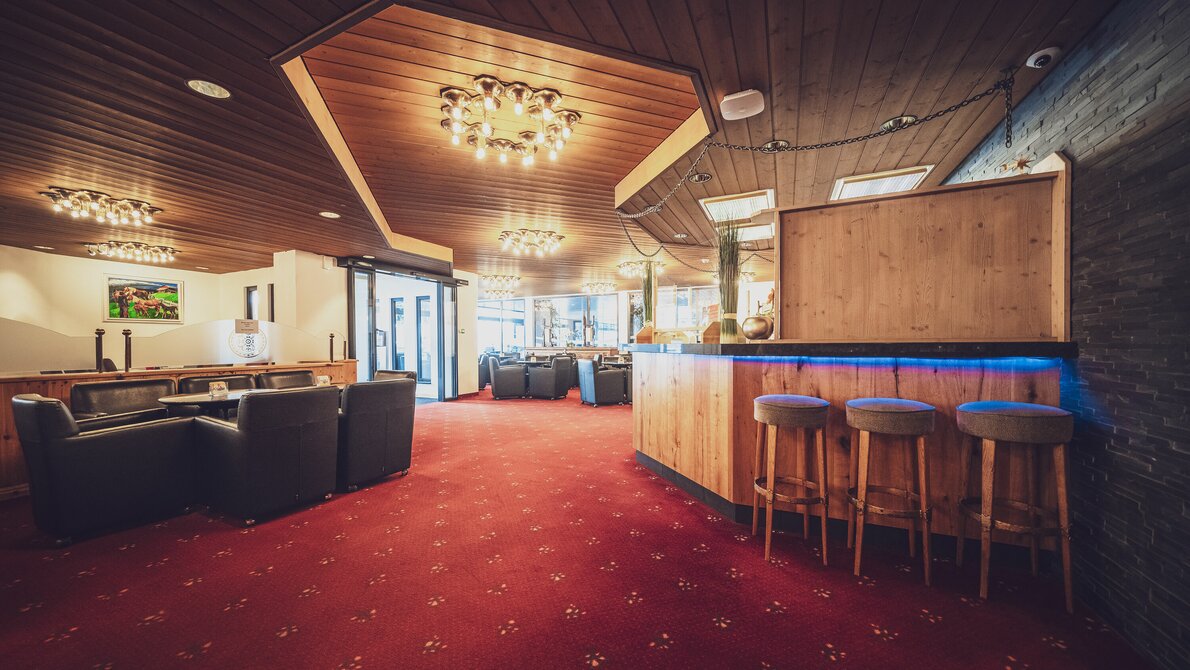 Hotellobby inkl. Bar mit Barhockern, Clubtischen und Loungesessel, roter Teppichboden | © Davos Klosters Mountains Hotellobby inkl. Bar mit Barhockern, Clubtischen und Loungesessel, roter Teppichboden | © Davos Klosters Mountains