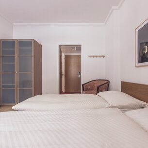 Double bed room with closet and lounge chair | © Davos Klosters Mountains