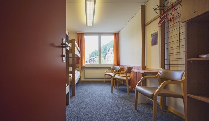 Mehrbettzimmer mit Stühlen und Stockbetten | © Davos Klosters Mountains