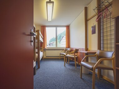 Mehrbettzimmer mit Stühlen und Stockbetten | © Davos Klosters Mountains