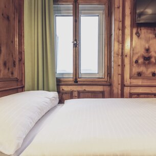 Hotelbett mit Holzvertäfelung | © Davos Klosters Mountains
