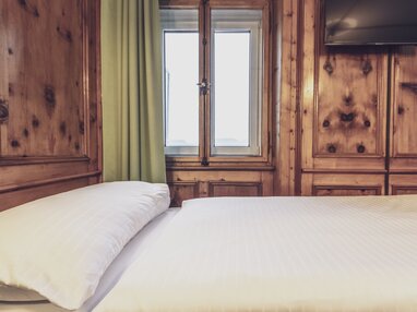 Hotelbett mit Holzvertäfelung | © Davos Klosters Mountains