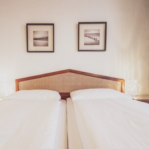 Hotel bed with pictures on the wall | © Davos Klosters Mountains
