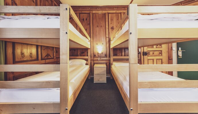 Two bunk beds in a shared room at the Hotel Montana with a beautiful wooden wall. | © Davos Klosters Mountains