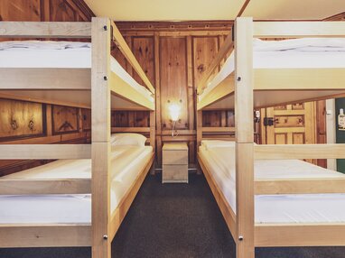 Zwei Stockbetten in einem Vierbettzimmer im Montana mit schöner Holzwand. | © Davos Klosters Mountains