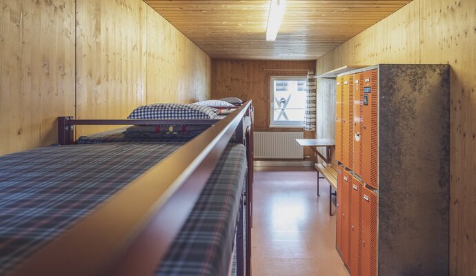 Room with multiple double bunk beds and lockers | © Davos Klosters Mountains 