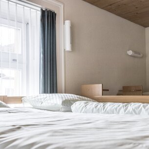 Mehrere schlichte Einzelbetten in einem Zimmer im Sporthof. | © Davos Klosters Mountains
