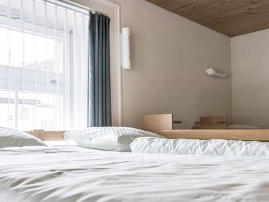 Mehrere schlichte Einzelbetten in einem Zimmer im Sporthof. | © Davos Klosters Mountains